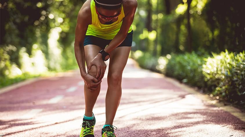 Outdoor athlete suffering from a sports injury on a running path