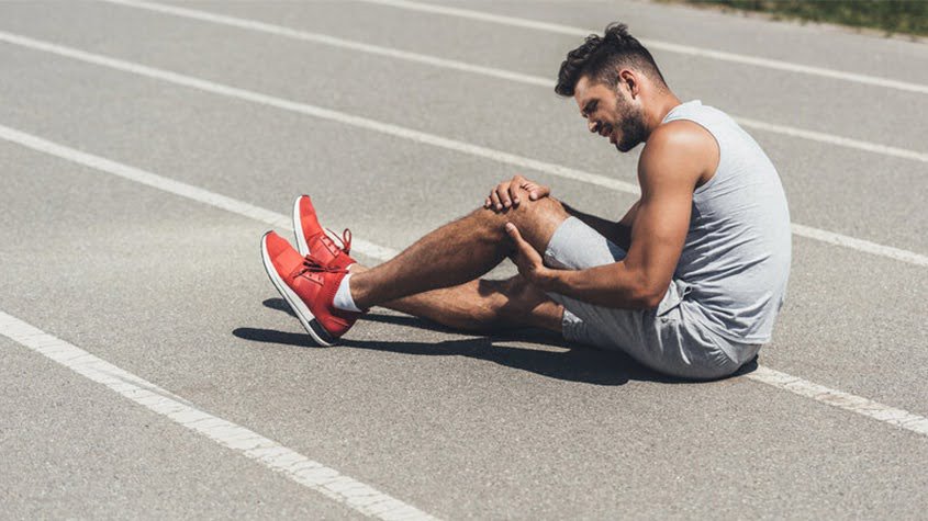 Athlete holding his injured knee after a sports injury on the track