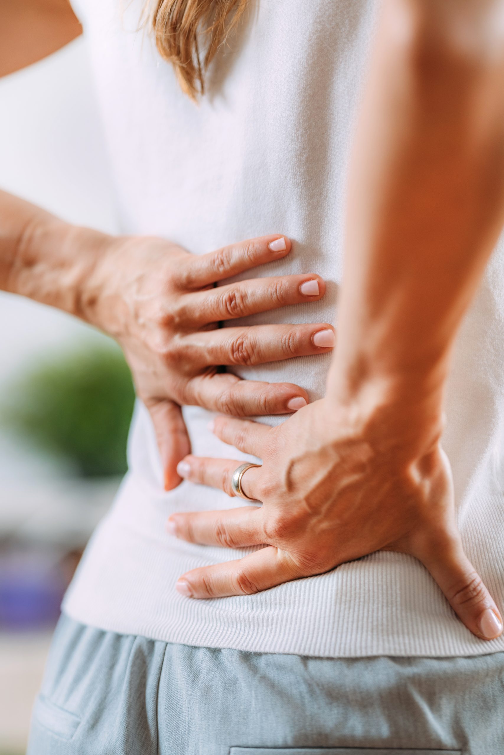 Woman holding her lower back, suggesting back pain or discomfort.